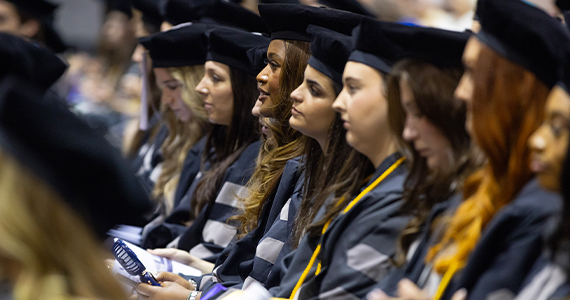 veterinary students in caps and gowns seated in the field house
